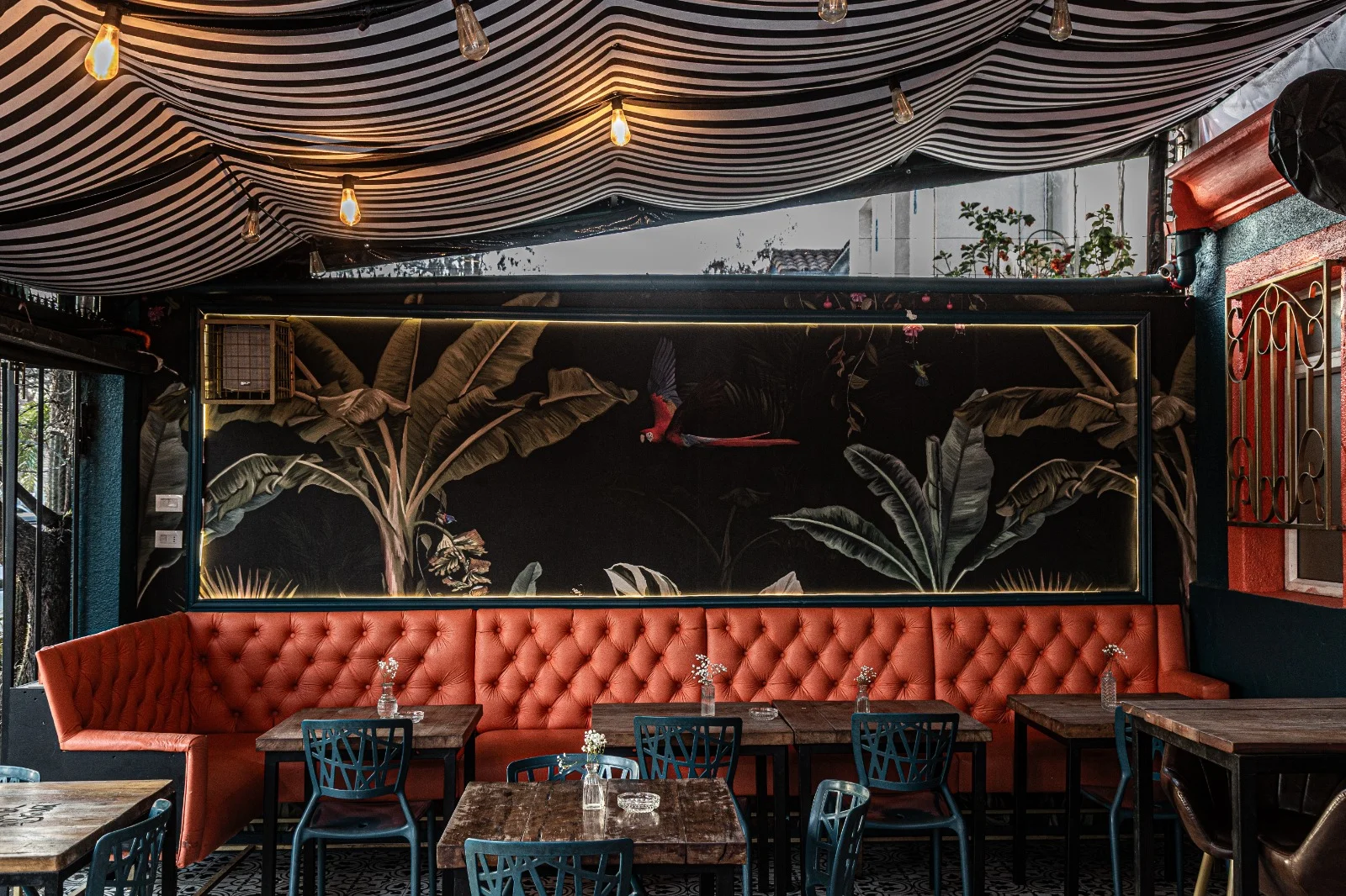 Diseño de salón de restaurante con mural botánico, banca tapizada e iluminación ambiental