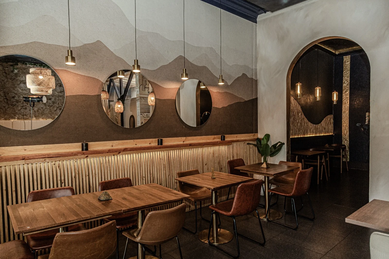 Interiorismo de restaurante con salón, mobiliario en madera e iluminación cálida